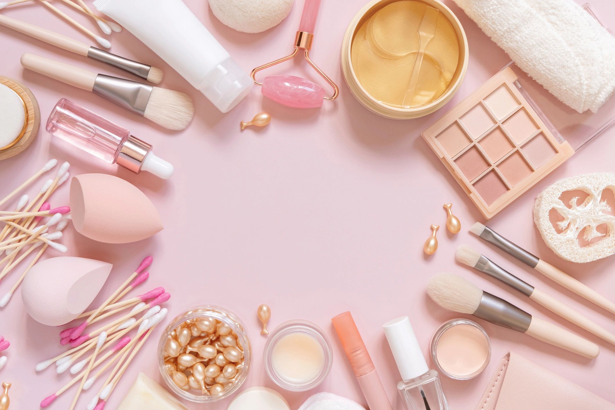 Productos de skincare en fondo rosa pastel