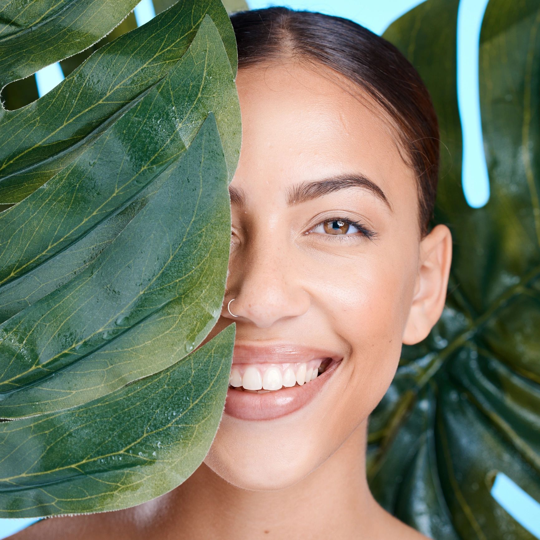 Retrato de mujer sonriendo con hoja verde, belleza natural