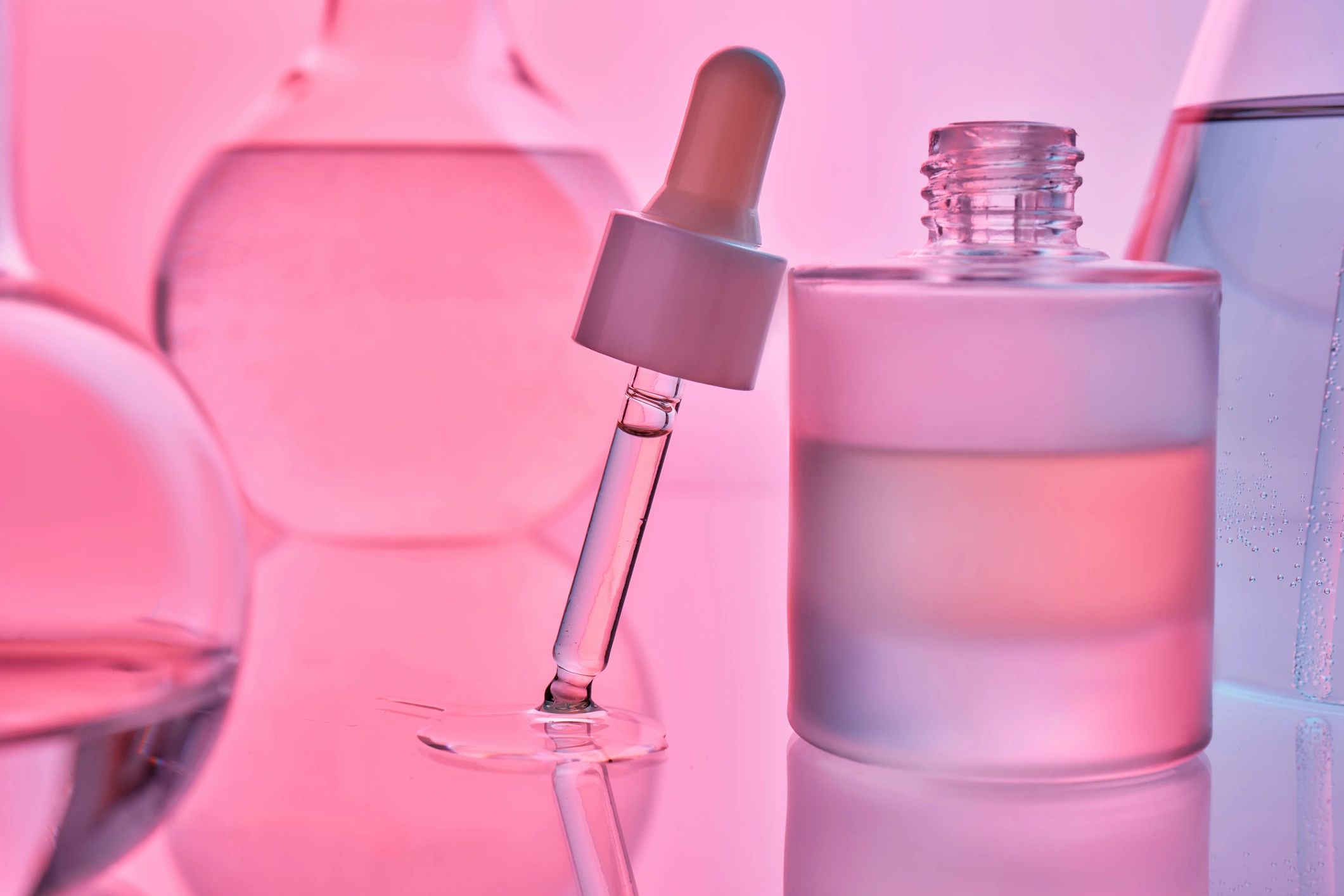 Gotero de sérum sobre fondo rosa, estética de laboratorio